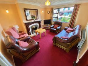 een woonkamer met lederen meubels en een open haard bij Kilbroney Rest in Rostrevor