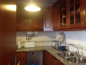 una cocina con armarios de madera y fregadero en Casa do Baleal, en Baleal