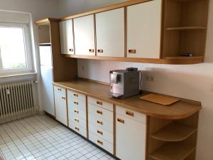 a kitchen with white cabinets and a microwave on a counter at Gästehaus Alm-Blick in Murrhardt