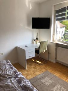 a bedroom with a desk with a chair and a television at Gästehaus Alm-Blick in Murrhardt