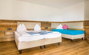 twee bedden in een kamer met houten vloeren bij Daarhof in Wagrain