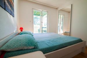 a bedroom with a bed with green sheets and a mirror at Apartments Radić in Bol