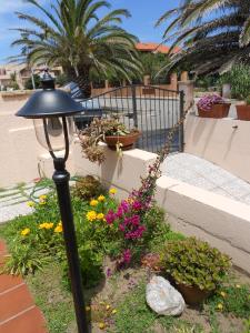 a black lamp in a garden with flowers at Ajò da Patrizia in Santa Teresa Gallura