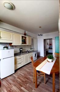 a kitchen with white cabinets and a wooden table and a dining room at Apartma MB-Center in Maribor