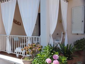 a porch with white curtains and flowers on a balcony at Ajò da Patrizia in Santa Teresa Gallura