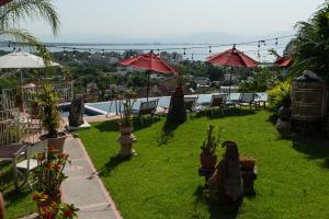 un patio con piscina, sillas y sombrillas en Villa Bella Bed & Breakfast Inn, en Cruz de Huanacaxtle