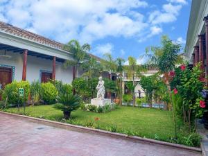 a garden in front of a house with a statue at La Casa del Marqués in Comitán
