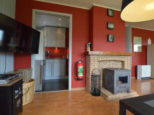 ein Wohnzimmer mit Kamin und roten Wänden in der Unterkunft Elegant Chalet in Malmedy with Private Garden in Malmedy