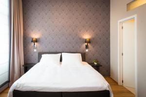 - une chambre avec un grand lit blanc et deux lampes dans l'établissement B&B Avenue Deschanel, à Bruxelles