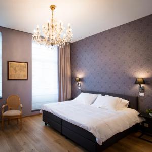 a bedroom with a large bed and a chandelier at B&B Avenue Deschanel in Brussels