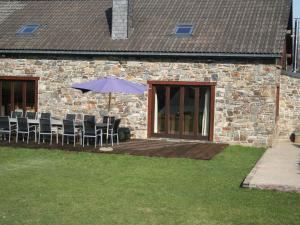a patio with chairs and an umbrella in front of a building at Beautiful Holiday Home in Beverc with Sauna in Malmedy