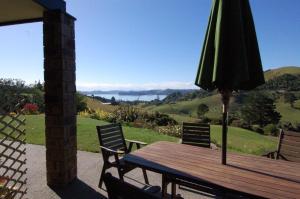 a wooden table with a umbrella and two chairs at Ohuka Place Homestay in Whitianga