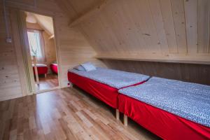 a bedroom with a red bed in a wooden room at Holiday Resort & Camping InterCamp'84 in Łeba +60 photos