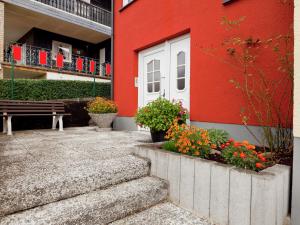 a red building with a white door and a bench at Apartment near the Nurburgring with terrace in Hillesheim