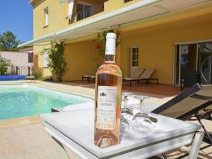 a bottle of wine sitting on a table next to a pool at Spacious villa in Vidauban with seasonal private pool in Vidauban