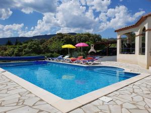 a swimming pool with chairs and umbrellas on a house at Stylish villa with private pool in Félines-Minervois