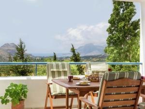 LefkogeiaにあるModish Villa in Lefkogia Crete with Swimming Poolの山の景色を望むバルコニー(テーブル、椅子付)