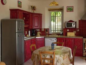 a kitchen with red cabinets and a table and a refrigerator at Magnificent holiday home with pool in Oppède