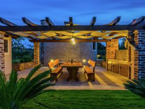 a patio with a wooden pergola with a table and benches at Lovely holiday home in Fazana with swimming pool in Štinjan