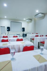 a conference room with white tables and red chairs at Cordela Inn HM Yamin Medan in Medan