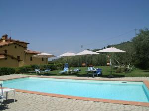 una piscina con sillas y sombrillas en Belvilla by OYO Podere Pulicciano Cantina, en Pian di Scò