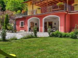 ein rotes Haus mit einem Balkon und einem Hof in der Unterkunft Belvilla by OYO Il melo bianco in Caldes