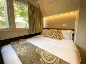 um quarto com uma cama grande e uma janela grande em ST Signature Bugis Beach em Singapura