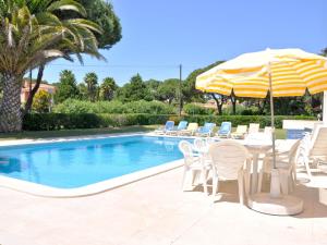 a pool with a table and chairs and an umbrella at Spacious Villa in Vilamoura with Barbecue in Vilamoura