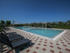a large swimming pool with chairs at Quaint Holiday Home in Grosseto with Beach Nearby in Grosseto