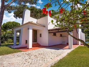 a white house with red flowers in the yard at Lovely villa in Vilamoura with private pool in Vilamoura