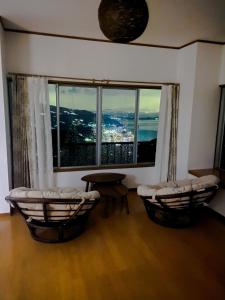 Habitación con 2 sillas, mesa y ventana en みーしぐリゾート(MYSIG RESORT) en Atami