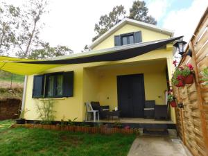 una pequeña casa amarilla con una puerta negra en LOCATIONS VERT EDEN, en La Plaine des Cafres