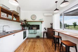 una cucina con pareti bianche, pavimenti in legno e un orologio sul muro di Toms Cottage - "Wilgowrah" -A Country Escape a Mudgee
