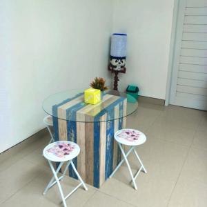 a glass table with two stools and a glass table with a table at Pigeon House Nusa Dua in Nusa Dua