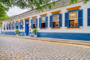 a cobblestone street in front of a building with blue shutters at Mara Palace Hotel in Vassouras