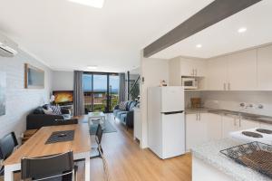 a kitchen with a table, chairs and a refrigerator at Hydra Holiday Units in Merimbula