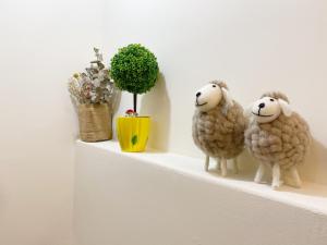 two stuffed sheep on a shelf with flowers and a plant at Yang's B&B in Jinning