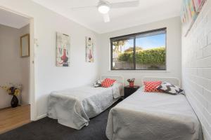 two beds in a room with a window at Hydra Holiday Units in Merimbula