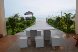 Briya Beachfront Residence في سيتشون: طاولة بيضاء وكراسي أمام المحيط