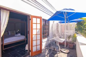 a balcony with a bed and a blue umbrella at Boord Guest House in Stellenbosch