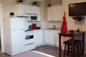 a kitchen with white cabinets and a table and a television at Business Traveler's Cozy Studio #21 by Amazing Property Rentals in Gatineau