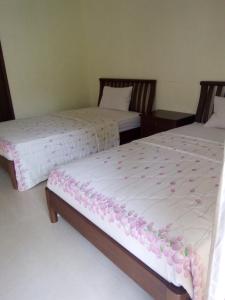 Villa Bora Paloma في Perdana: سريرين في غرفة عليها ورد وردي