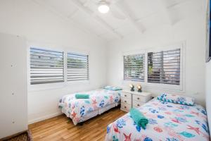 2 camas en un dormitorio con paredes y ventanas blancas en Blue River Apartments, en Wooli