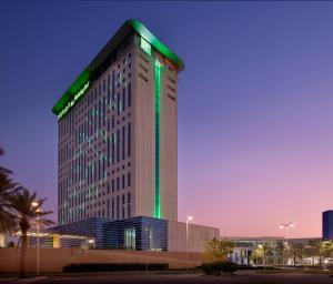 un edificio alto con luces verdes. en Holiday Inn & Suites - Dubai Festival City Mall, an IHG Hotel, en Dubái