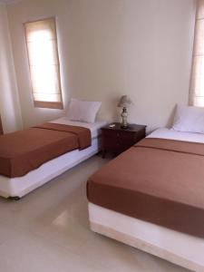 Villa Bora Paloma في Perdana: سريرين في غرفة بها نافذتين