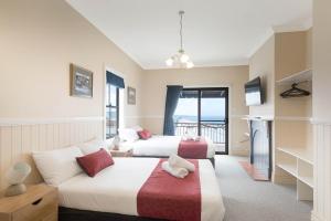 a hotel room with two beds and a balcony at Heritage House Motel & Units in Eden