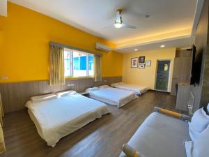 three beds in a room with yellow walls at I WoW in Xiaoliuqiu