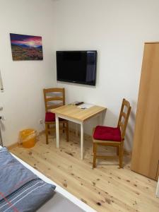 Cette chambre dispose d'une table, de deux chaises et d'une télévision. dans l'établissement Apartmenthaus Schlanow, à Detmold