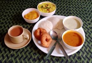 a plate of food with two donuts and two cups of coffee at KABINI FARM STAY in Antarasante +17 photos