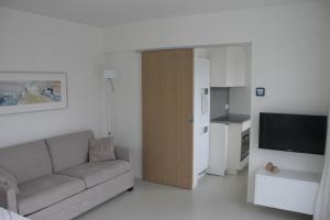 een woonkamer met een bank en een televisie bij Penthouse Sun Corner Knokke in Knokke-Heist